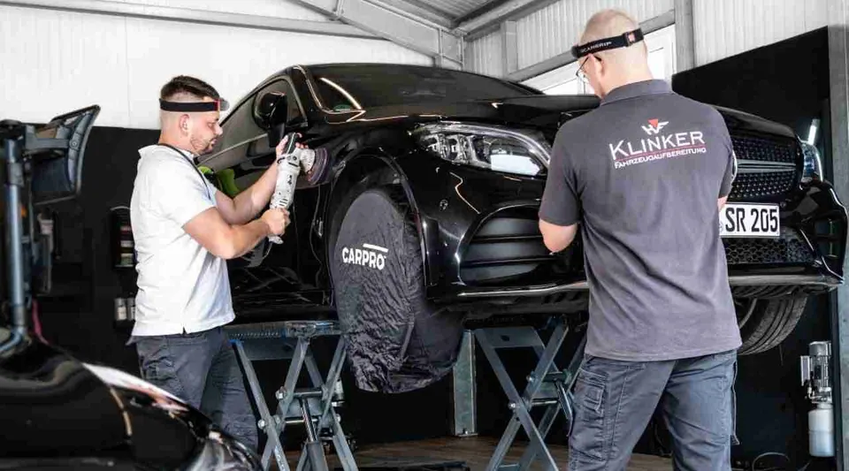 Mitarbeiter von Klinker Fahrzeugaufbereitung bei der professionellen Außenaufbereitung eines Autos
