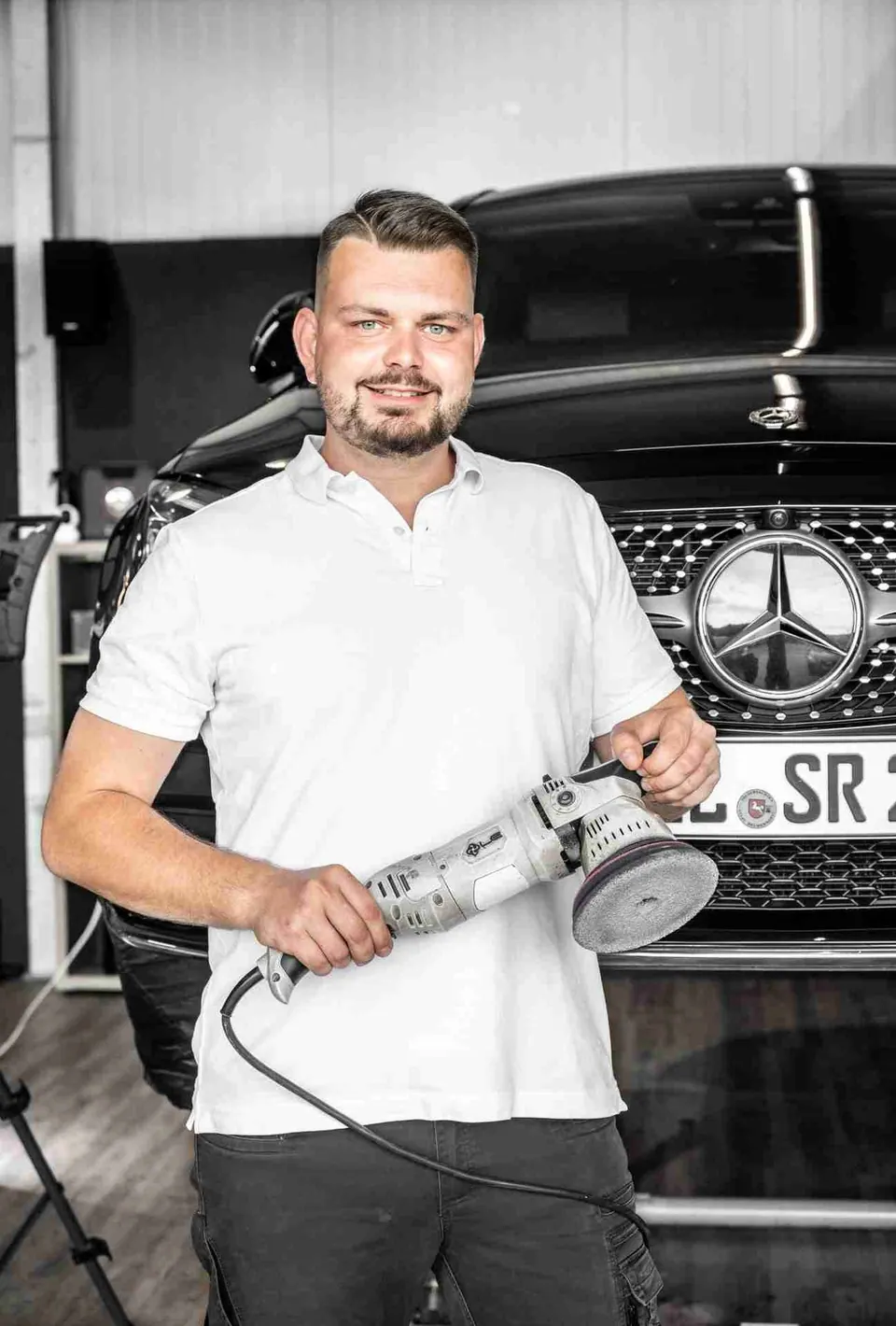 Professionelle Fahrzeugaufbereitung - Mitarbeiter mit Poliermaschine vor einem Mercedes-Benz